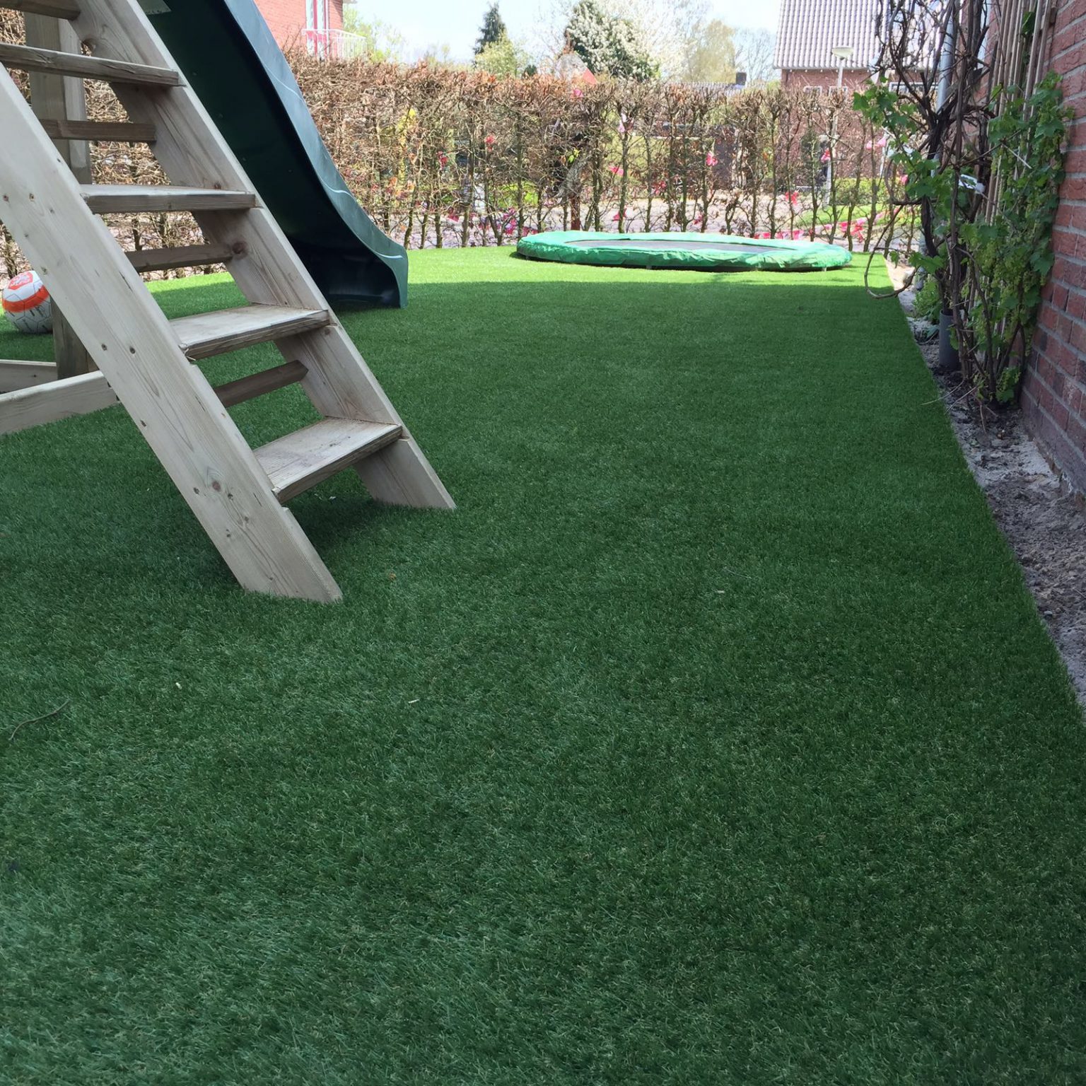 Fijne kidsproof tuin met kunstgras wat tegen een stootje kan